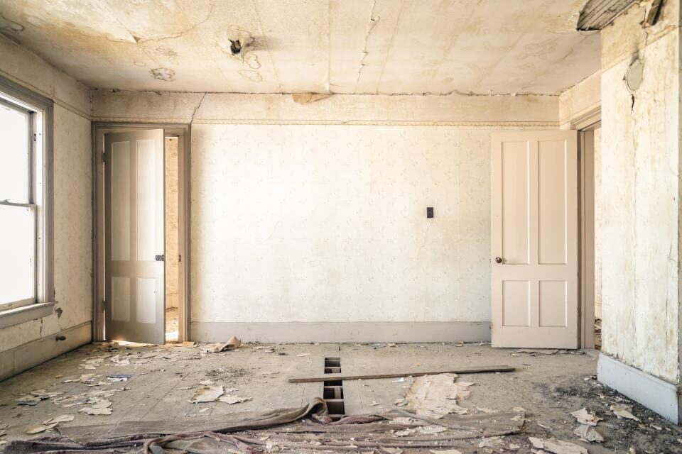 Empty room under renovation with bare walls and an unfinished floor